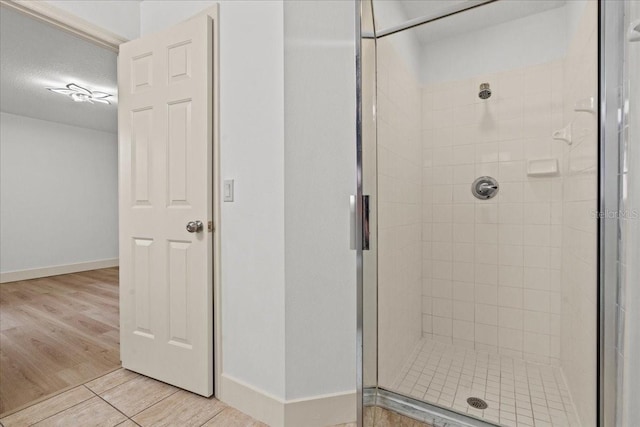 bathroom featuring a textured ceiling, a shower with shower door, and hardwood / wood-style flooring