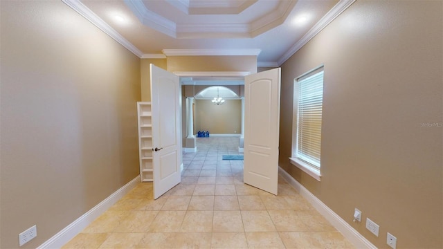 hallway with a tray ceiling, ornamental molding, a notable chandelier, and light tile patterned flooring