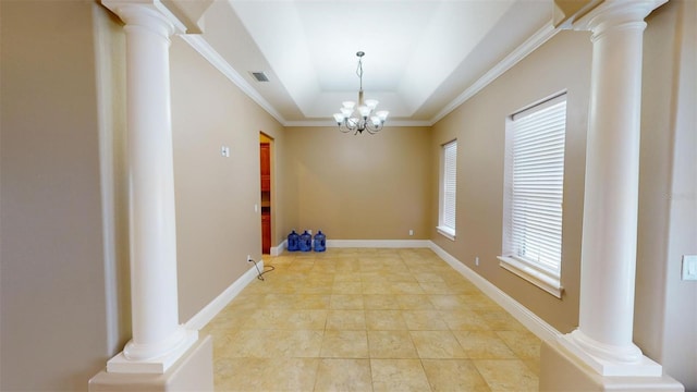 empty room with ornamental molding, a chandelier, a raised ceiling, and decorative columns