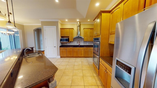 kitchen featuring decorative light fixtures, wall chimney range hood, stainless steel appliances, sink, and backsplash