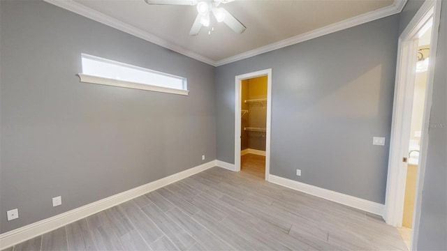 interior space featuring ceiling fan, crown molding, a spacious closet, and a closet