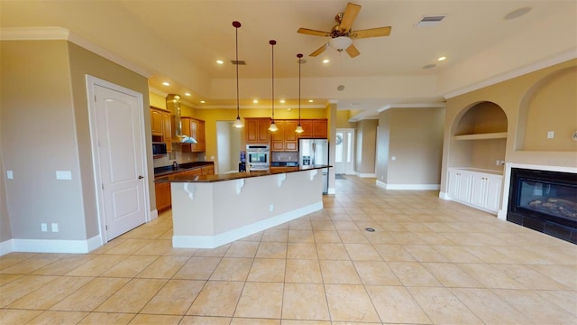 kitchen featuring a kitchen island, decorative light fixtures, built in shelves, stainless steel appliances, and a tiled fireplace