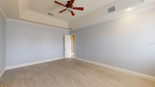 spare room with ceiling fan, ornamental molding, a raised ceiling, and light wood-type flooring