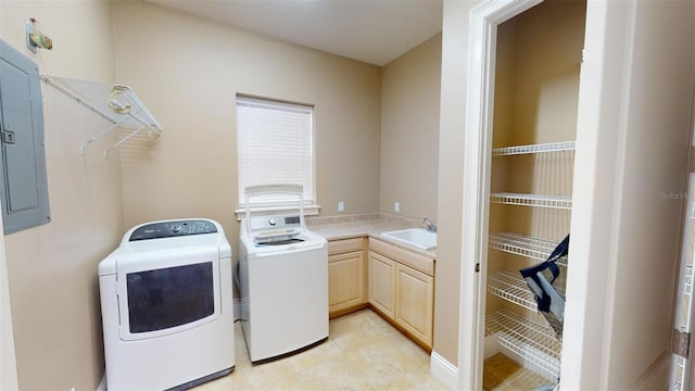 laundry area featuring electric panel, washing machine and dryer, sink, light tile patterned floors, and cabinets