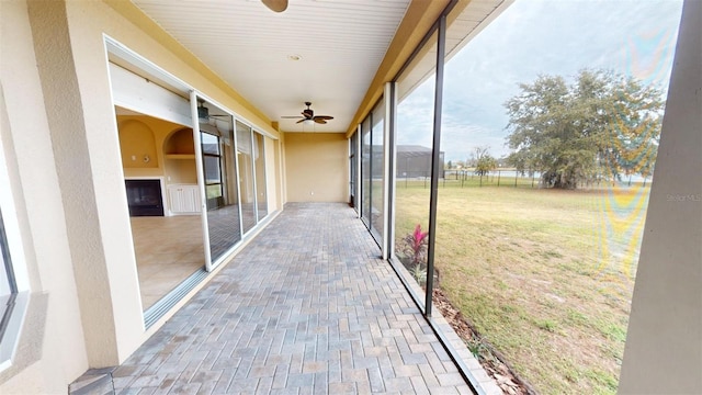 unfurnished sunroom with ceiling fan