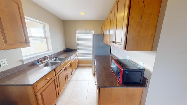 kitchen featuring light tile patterned flooring, stainless steel fridge, and sink