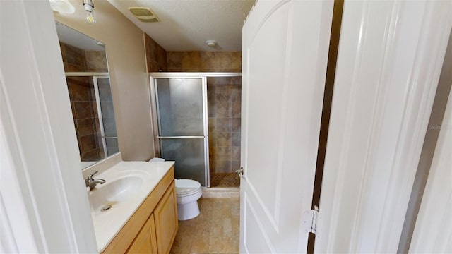 bathroom featuring toilet, vanity, tile patterned flooring, and a shower with door