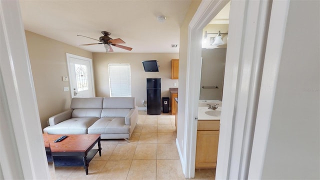 tiled living room featuring ceiling fan and sink