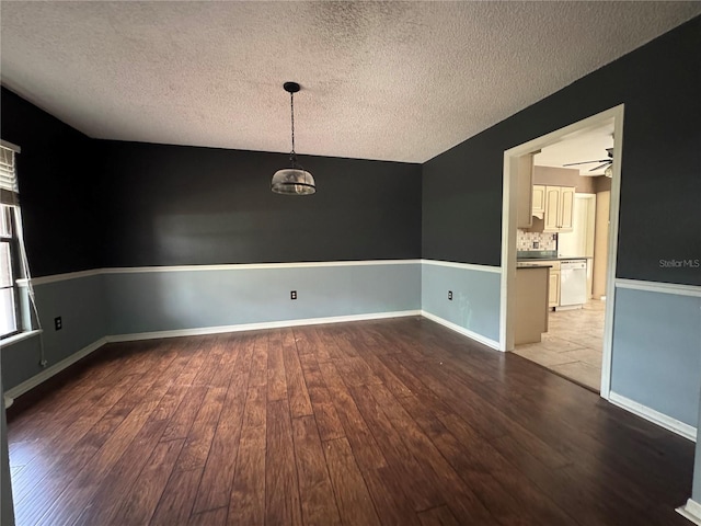 empty room with light wood-type flooring, a ceiling fan, baseboards, and a textured ceiling