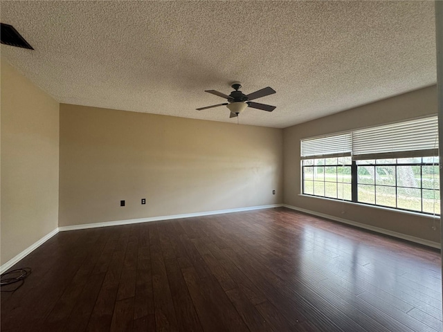 empty room featuring a textured ceiling, dark wood-style flooring, a ceiling fan, and baseboards