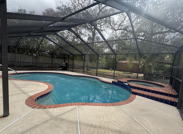 view of pool with glass enclosure, a fenced backyard, an outbuilding, a patio area, and a shed