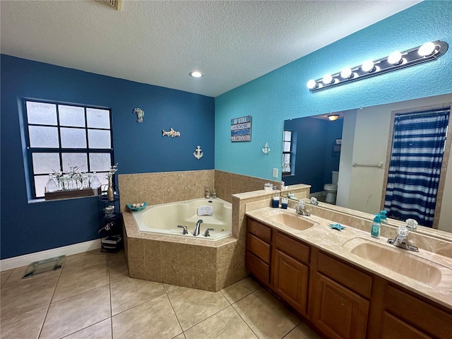 bathroom with a textured ceiling, tile patterned flooring, vanity, toilet, and a relaxing tiled tub