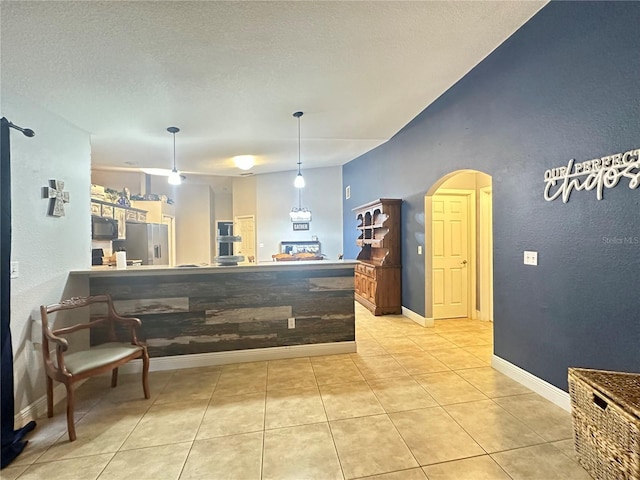 kitchen featuring decorative light fixtures, light tile patterned floors, stainless steel refrigerator with ice dispenser, and a textured ceiling