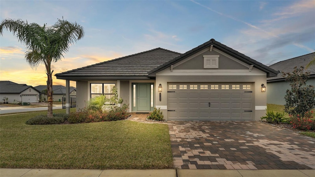 view of front of home with a garage and a lawn