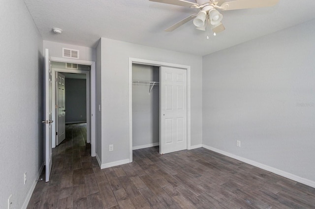 unfurnished bedroom featuring dark wood-type flooring, ceiling fan, and a closet