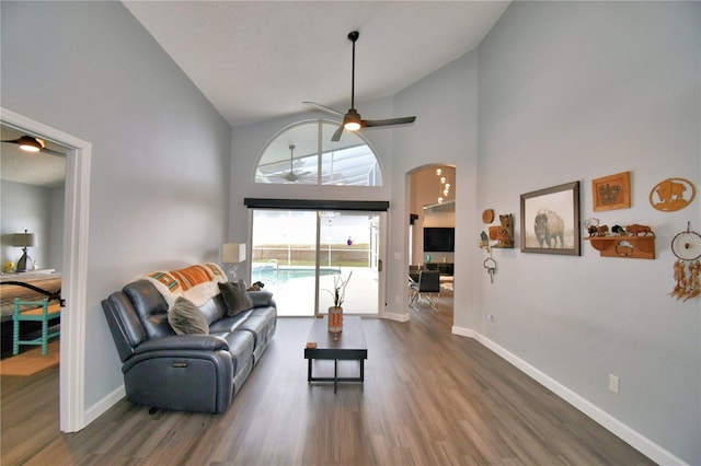 living room featuring dark wood-type flooring, high vaulted ceiling, and ceiling fan