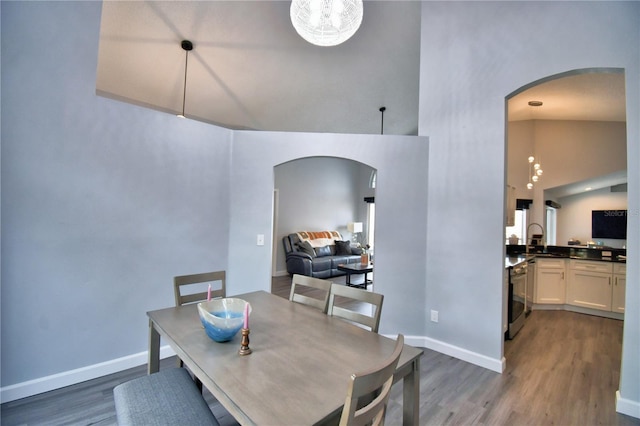 dining space with dark wood-type flooring, sink, and high vaulted ceiling