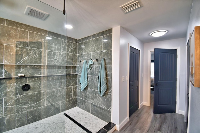 bathroom featuring hardwood / wood-style flooring and a tile shower