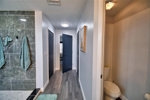 bathroom with wood-type flooring, toilet, and a shower