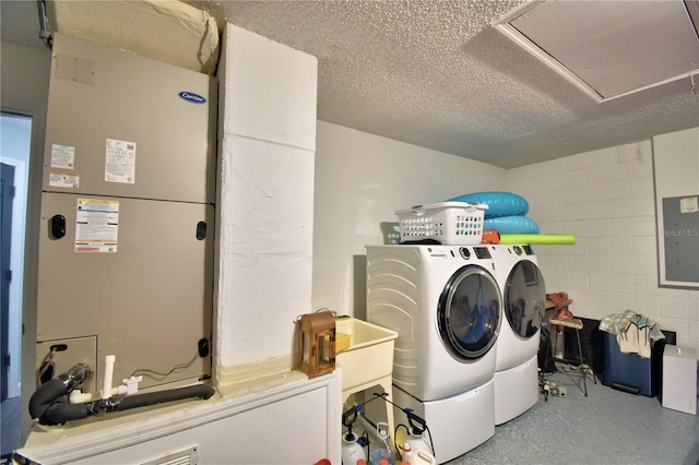 clothes washing area with heating unit, electric panel, and washer and dryer