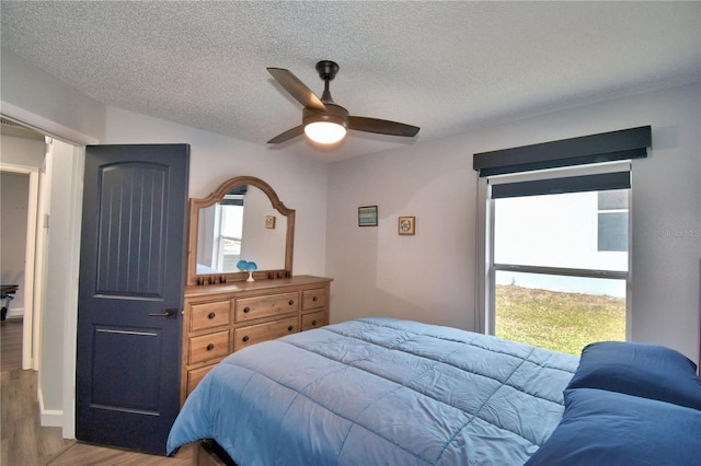 bedroom with hardwood / wood-style floors, a textured ceiling, and ceiling fan