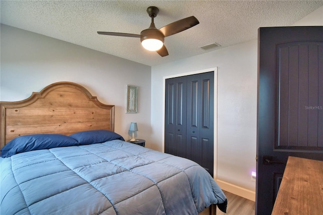 bedroom featuring hardwood / wood-style flooring, ceiling fan, a closet, and a textured ceiling