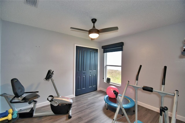 workout room with ceiling fan, hardwood / wood-style floors, and a textured ceiling