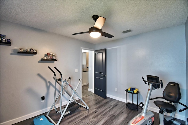 workout room featuring dark wood-type flooring, a textured ceiling, and ceiling fan