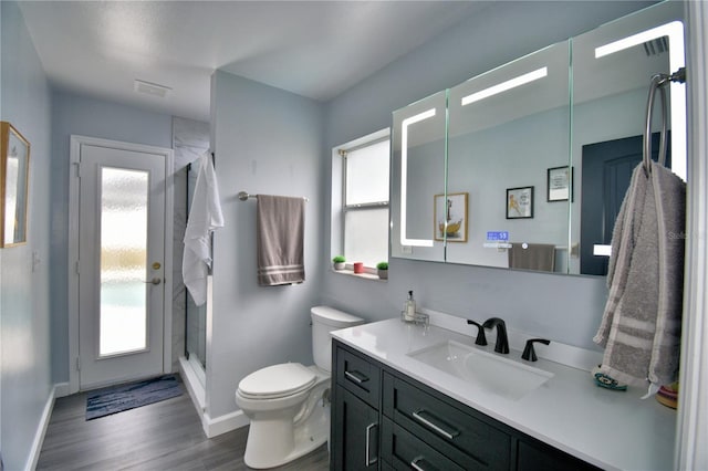 bathroom featuring a shower with door, vanity, hardwood / wood-style floors, and toilet