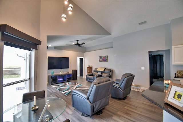 living room with ceiling fan, a textured ceiling, vaulted ceiling, and wood-type flooring