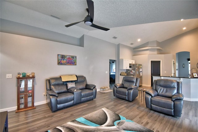 living room with ceiling fan, hardwood / wood-style floors, vaulted ceiling, and a textured ceiling