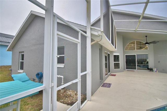 view of side of property with glass enclosure, ceiling fan, and a patio area