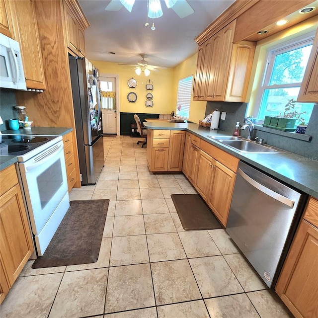 kitchen featuring appliances with stainless steel finishes, built in desk, sink, light tile patterned floors, and kitchen peninsula