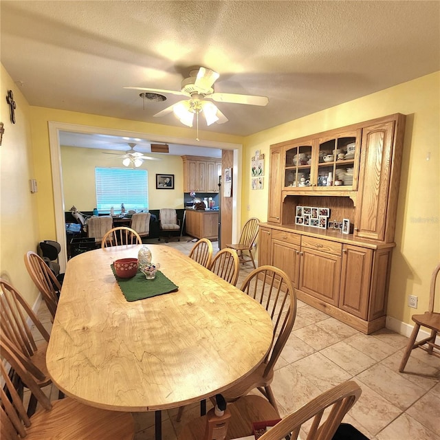 dining space featuring ceiling fan and a textured ceiling