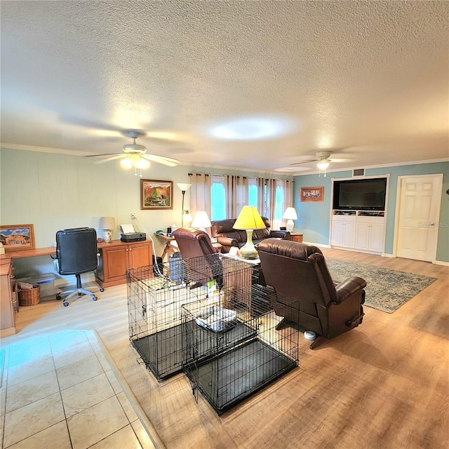 living room with ceiling fan, ornamental molding, and a textured ceiling