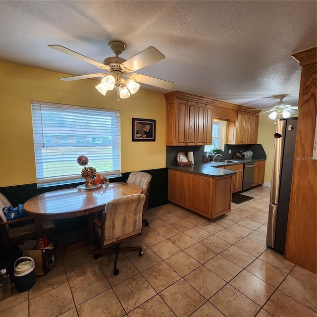 kitchen with ceiling fan, appliances with stainless steel finishes, light tile patterned floors, and a textured ceiling