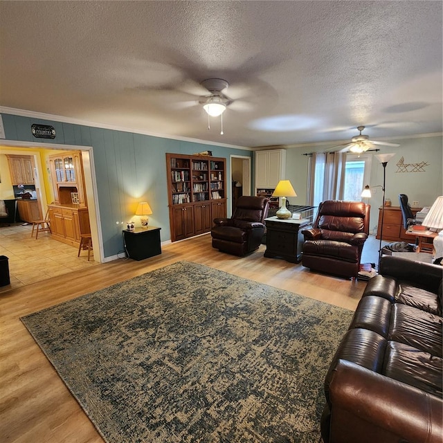 living room featuring crown molding, light hardwood / wood-style flooring, a textured ceiling, and ceiling fan