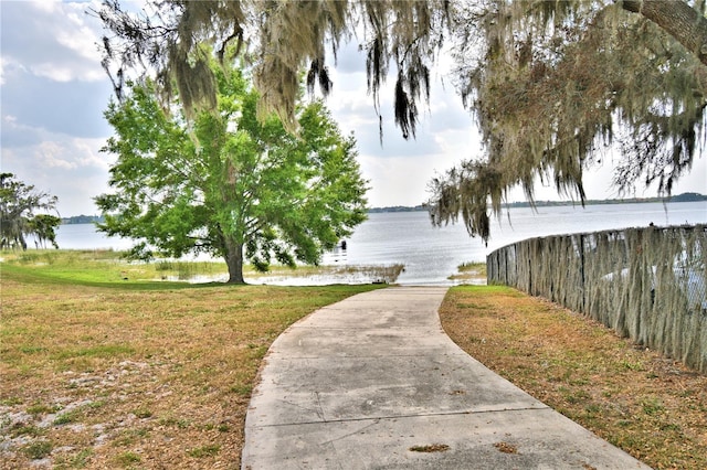 view of property's community with a water view and a lawn