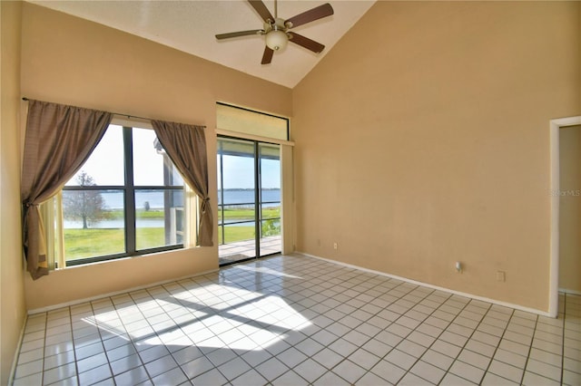 spare room featuring light tile patterned floors, high vaulted ceiling, ceiling fan, and a water view