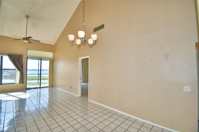 tiled spare room with ceiling fan with notable chandelier and high vaulted ceiling