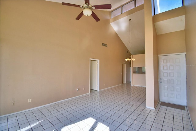 tiled empty room featuring ceiling fan with notable chandelier and high vaulted ceiling