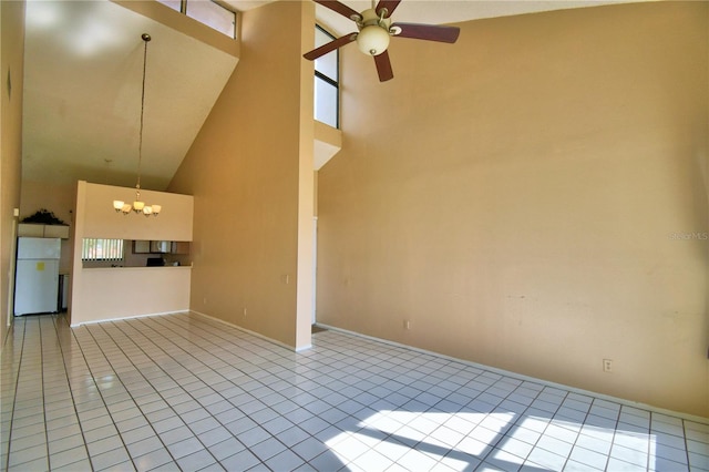 unfurnished living room featuring ceiling fan with notable chandelier, high vaulted ceiling, and light tile patterned flooring