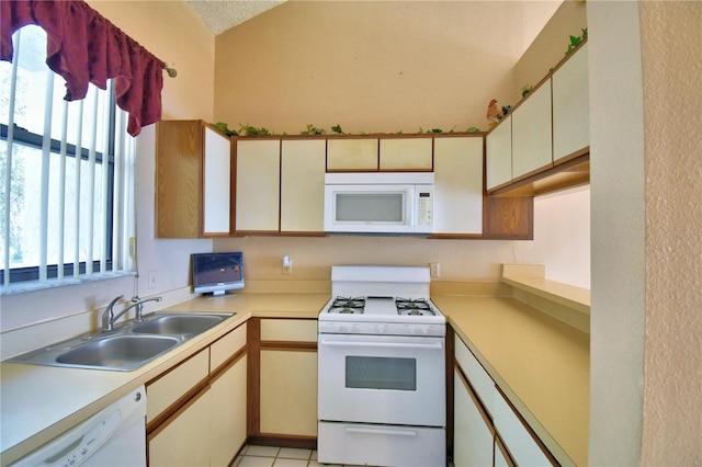 kitchen featuring a healthy amount of sunlight, sink, light tile patterned floors, and white appliances