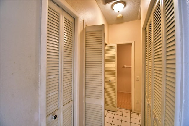 corridor with light tile patterned floors and a textured ceiling