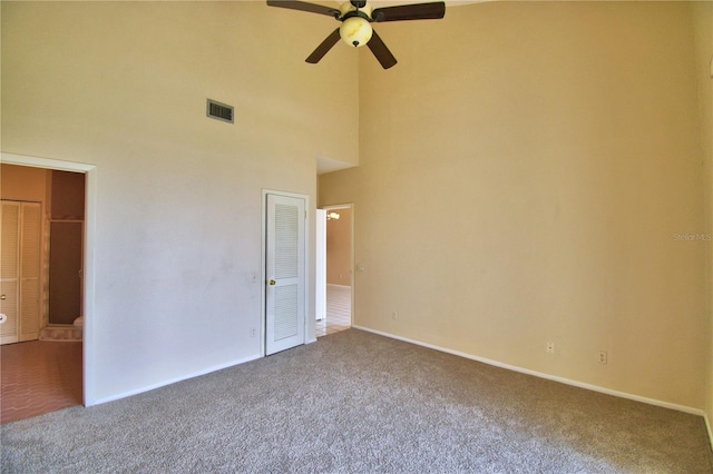 unfurnished bedroom featuring a towering ceiling, carpet floors, and ceiling fan