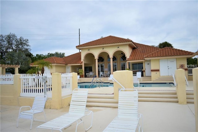 rear view of house featuring a community pool and a patio area