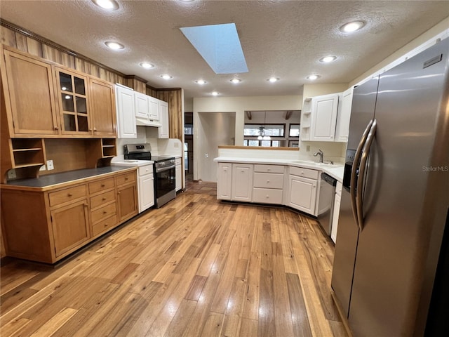 kitchen featuring sink, appliances with stainless steel finishes, a skylight, a textured ceiling, and kitchen peninsula