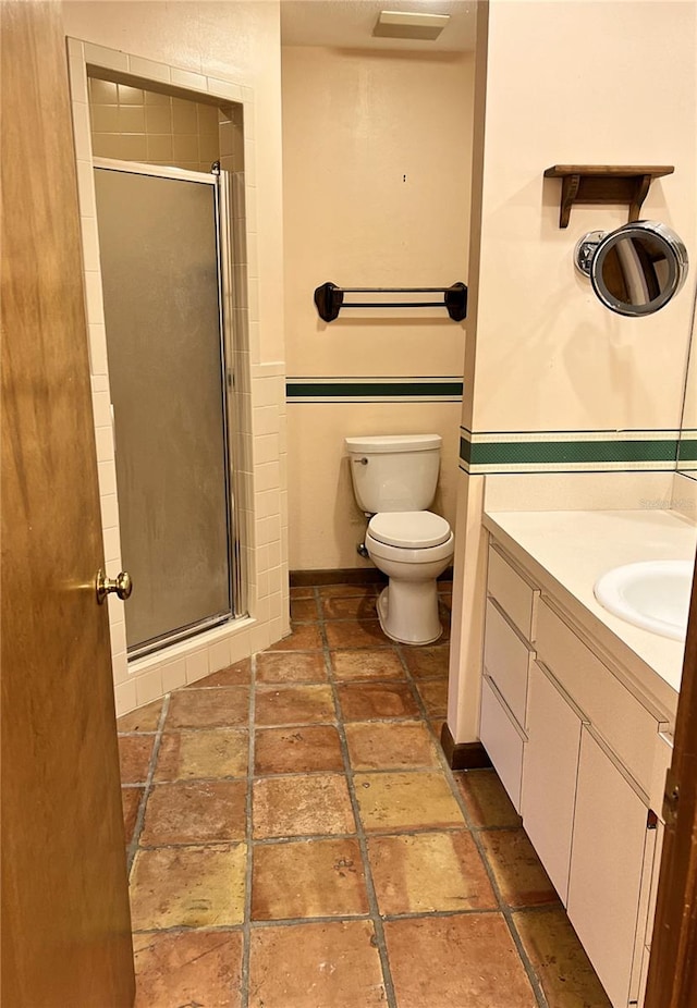 bathroom with vanity, toilet, and a shower with door