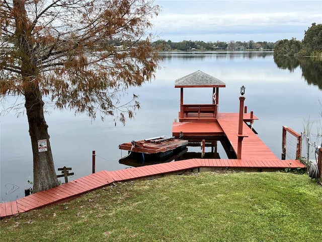 view of dock featuring a water view and a yard