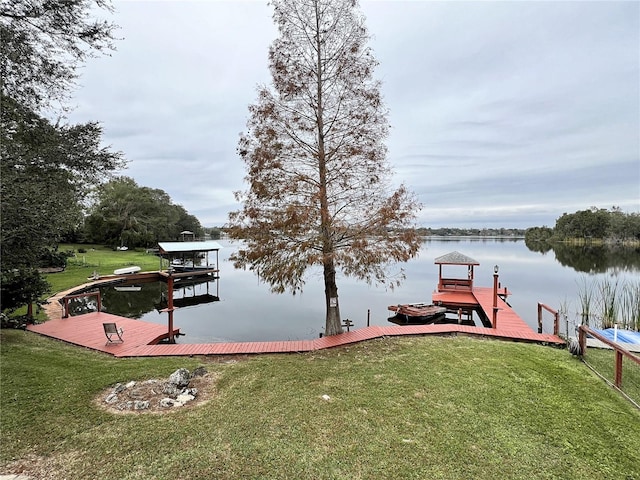 view of dock with a water view and a yard